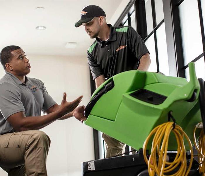 SERVPRO employee with equipment speaking to a customer